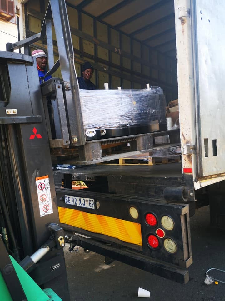 Forklift loading a wrapped machine into a Curth Movers truck